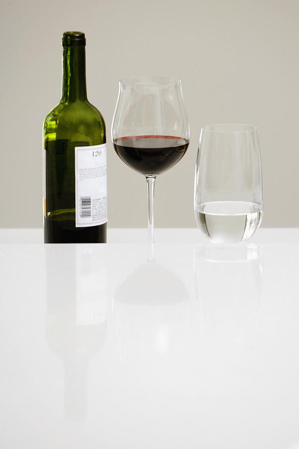 Close-up of a wine bottle with a glass of red wine and a glass of water on a dining table Photograph by Glowimages