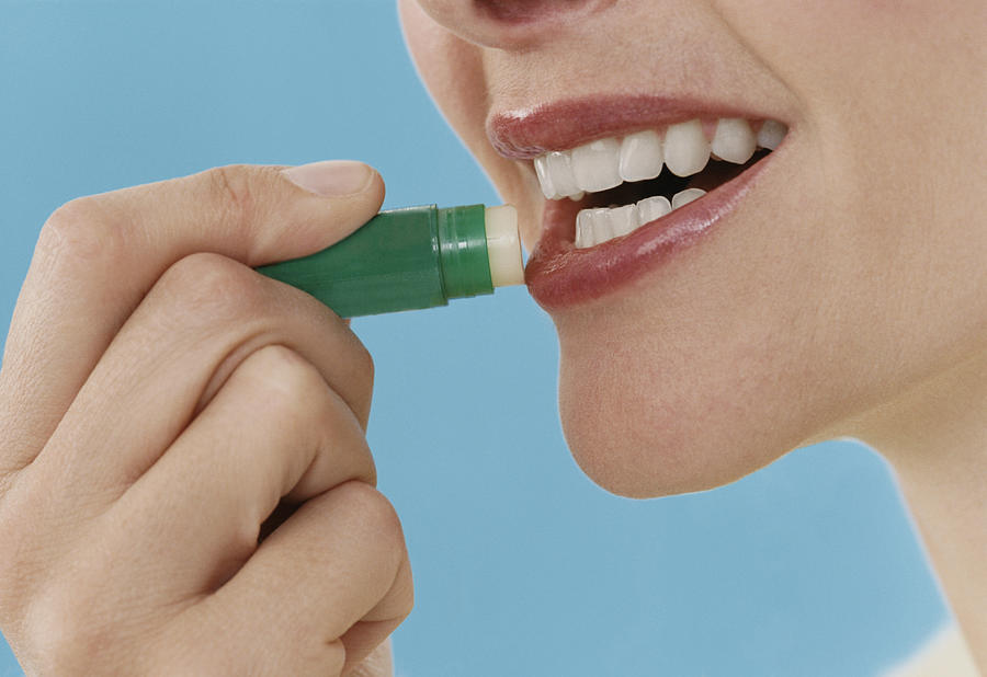 Close-Up of a Woman Applying Lip Balm Photograph by Digital Vision.