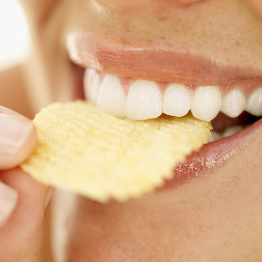 Close-up of a woman biting into a crisp Photograph by Stockbyte