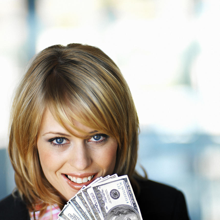 Close-up Of A Woman Holding Hundred Dollar Bills To Her Face Photograph by Stockbyte