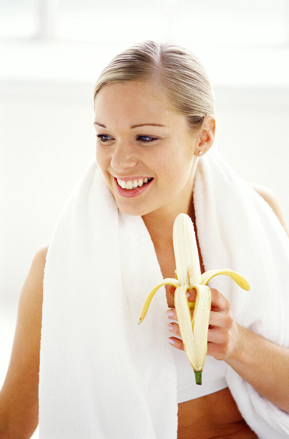 Close-up Of A Woman Wearing A Sweat Towel And Holding A Peeled Banana Photograph by George Doyle