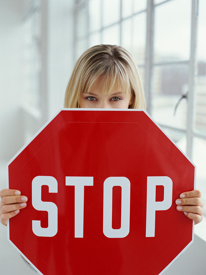 Close-up of a young woman holding a stop sign Photograph by Stockbyte