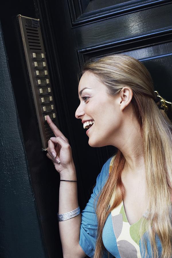 Close-up of a young woman pressing a doorbell Photograph by Glowimages