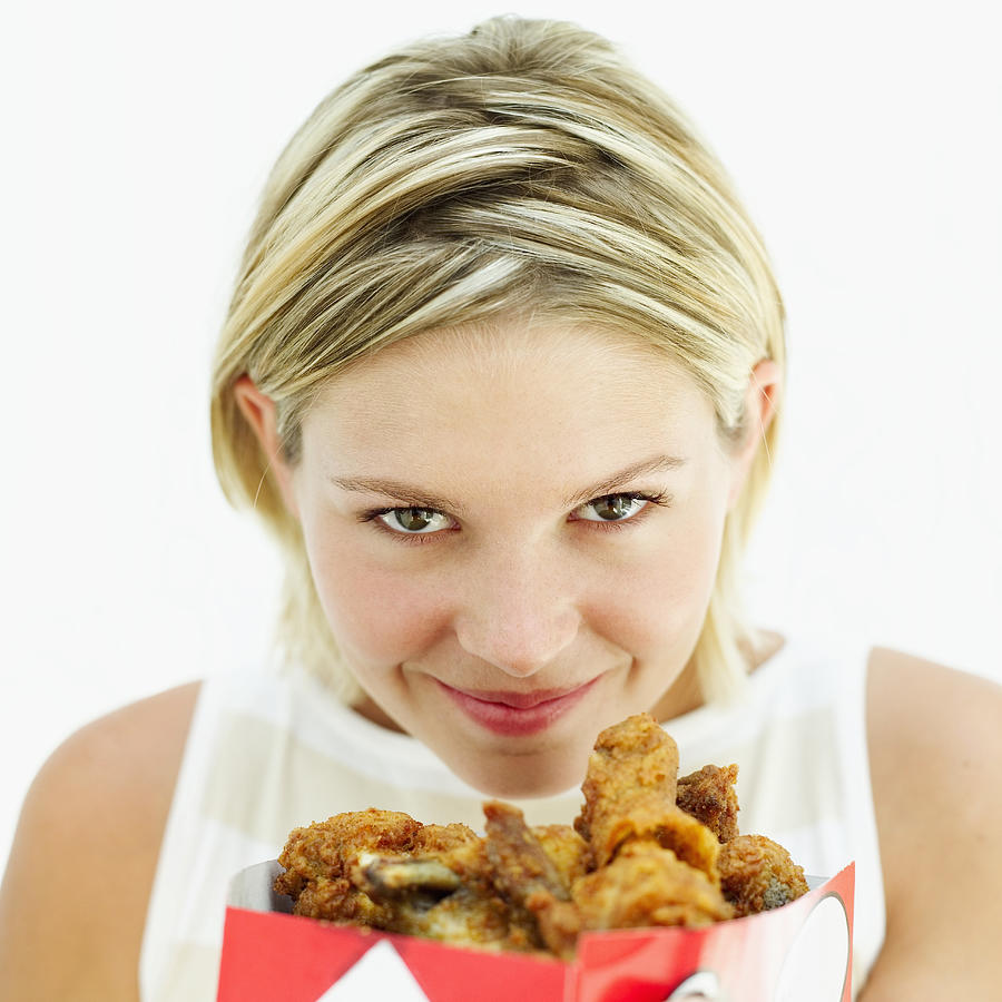 Close-up Of A Young Woman Smelling Fried Chicken Photograph by Stockbyte