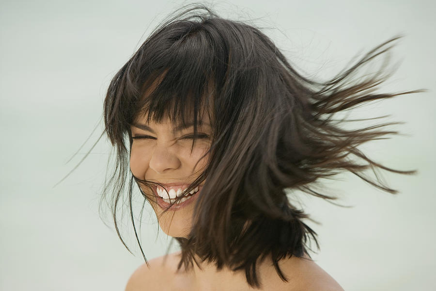 Close-up of a young woman smiling on the beach Photograph by Medioimages/Photodisc