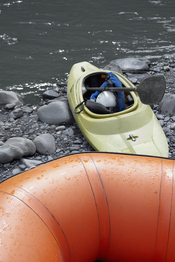 Close-up of an inflatable raft and a kayak at a riverbank Photograph by Glowimages