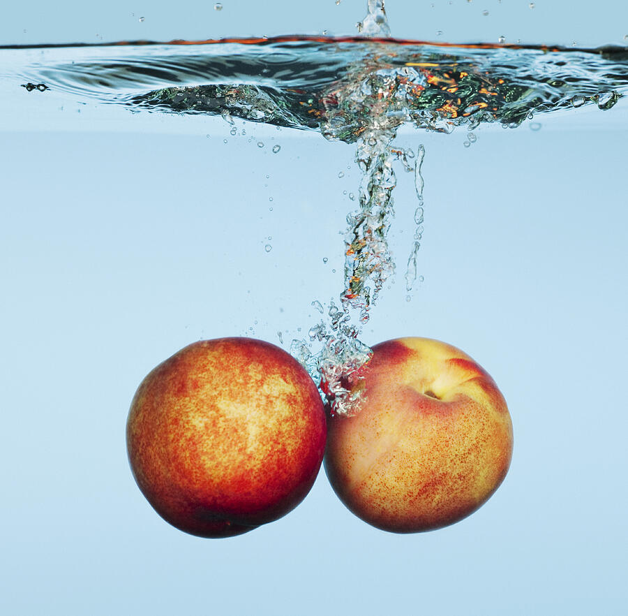 Close up of apples splashing in water Photograph by Martin Barraud