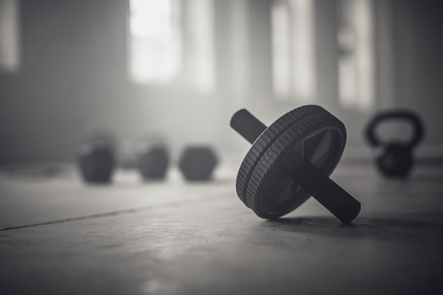Close up of barbell weights on floor of dark gym Photograph by John Fedele