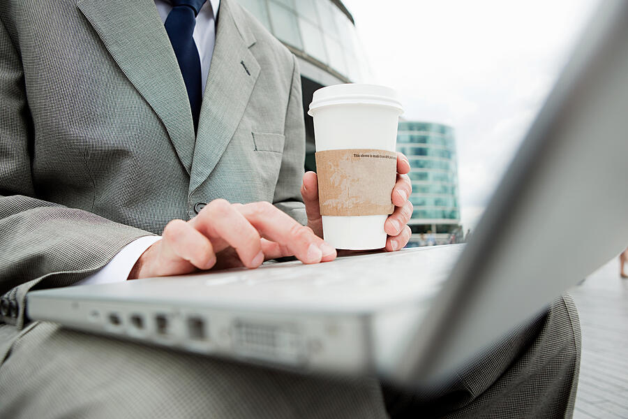 Close up of businessman with laptop and coffee outdoors Photograph by Image Source