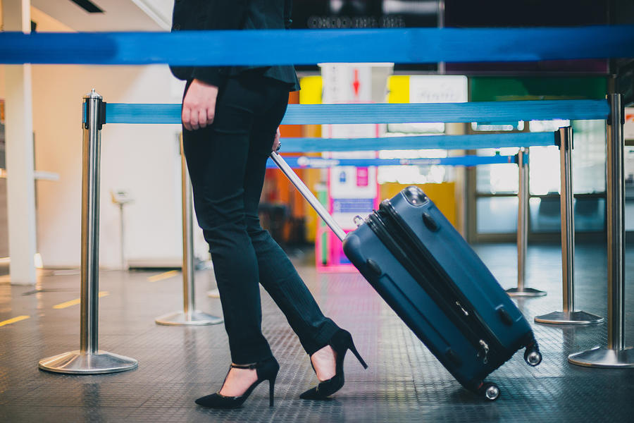 Close-up of businesswoman pulling suitcase to the check-in desk Photograph by Domoyega