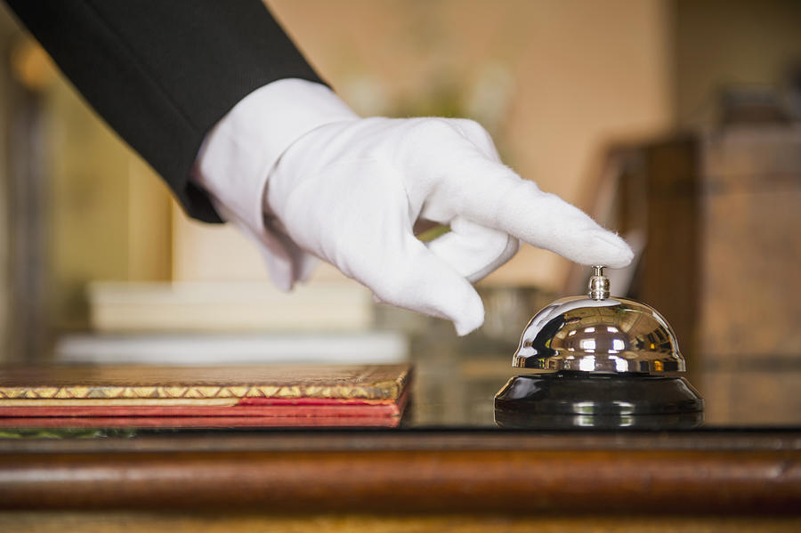 Close up of Caucasian butler ringing bell Photograph by Jacobs Stock Photography Ltd