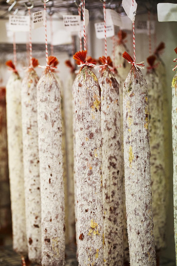 Close up of Chorizo sausages hanging from hooks in a charcuterie. Photograph by Mint Images