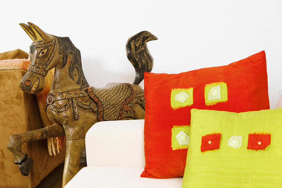 Close-up of cushions on a couch with a wooden horse Photograph by Glowimages