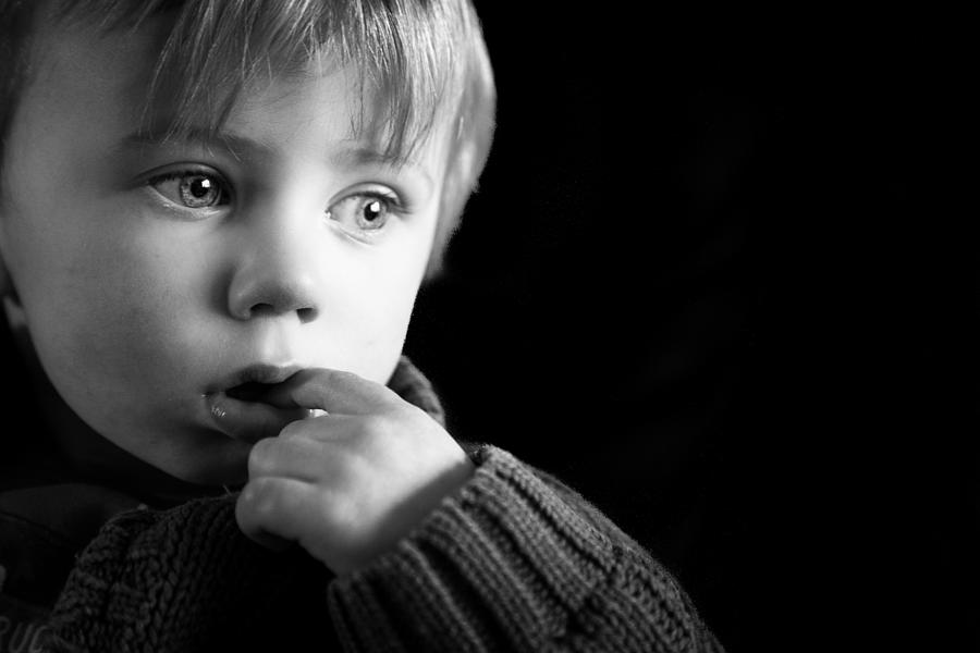 Close up of cute two year old caucasian little boy looking depressed and sad isolated on black background Photograph by Coldsnowstorm