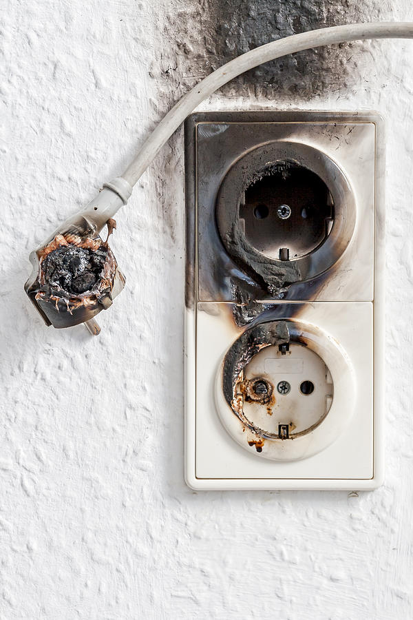 Close-up of electrical fire with the wire and wall plug Photograph by Senorcampesino