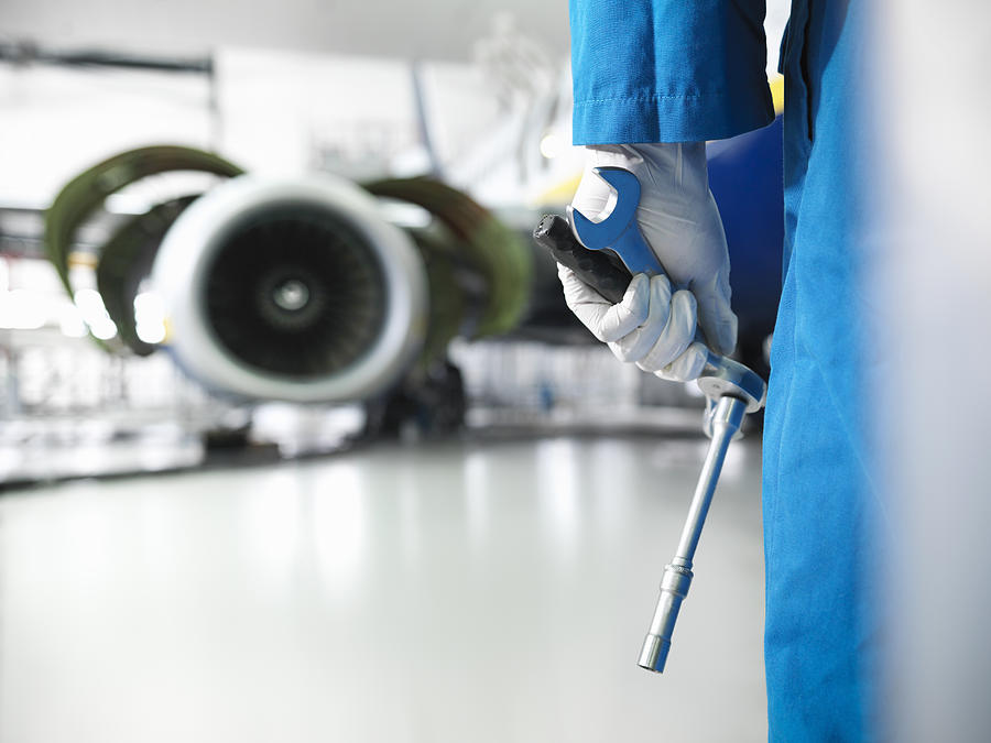 Close up of engineer holding tools in aircraft hangar Photograph by Monty Rakusen