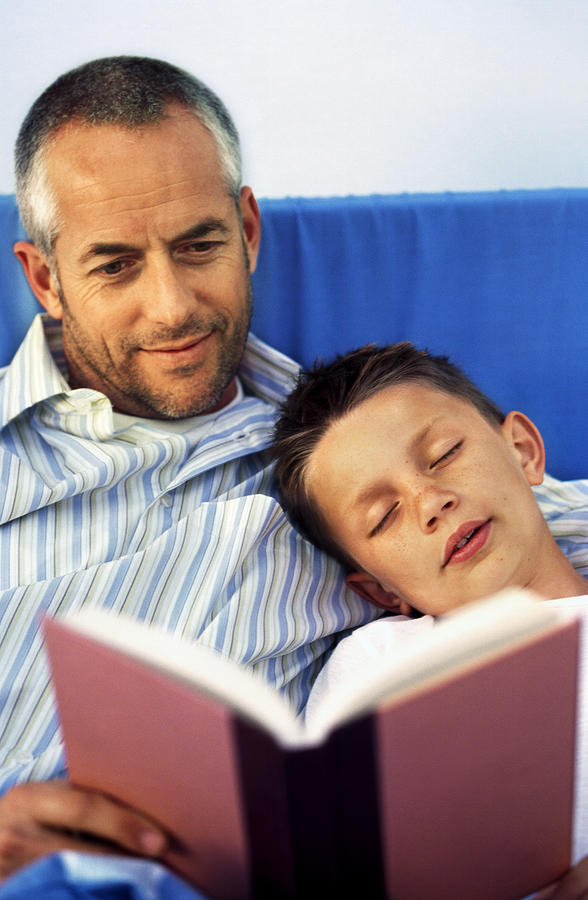 Close-up of father reading story to son (10-11) Photograph by Stockbyte