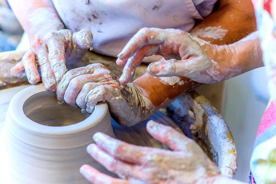Close up of female potter and mature student hands making pot on potters wheel Photograph by Sue Barr