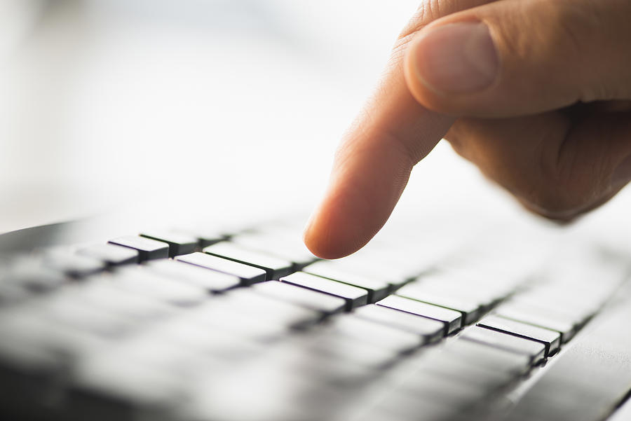 Close-up of finger typing on keyboard Photograph by Tetra Images