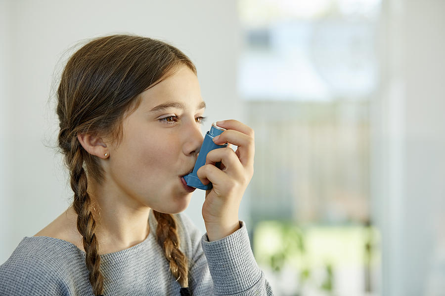 Close-up of girl using asthma inhaler at home Photograph by Nomad