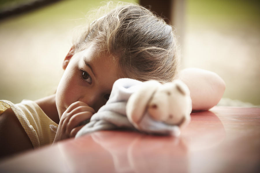 Close up of girl with stuffed animal sucking thumb Photograph by Adam Gault