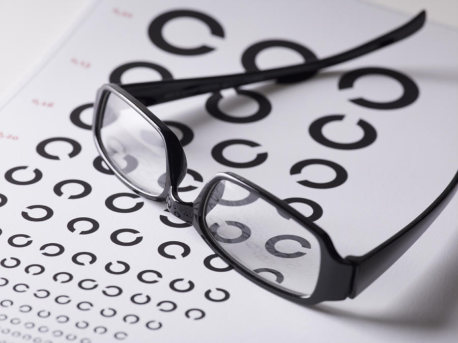 Close-up of glasses on eye exam chart Photograph by Larry Washburn