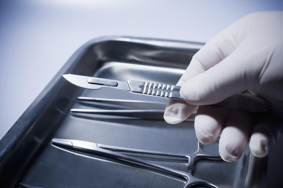 Close up of Hispanic doctor holding surgical equipment Photograph by REB Images