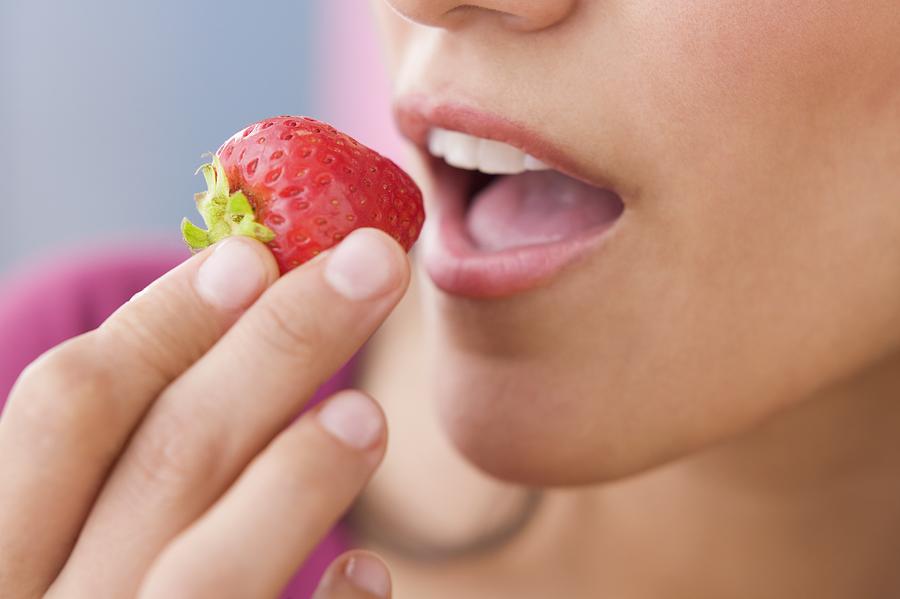 Close up of Hispanic woman eating strawberry Photograph by Jose Luis Pelaez Inc