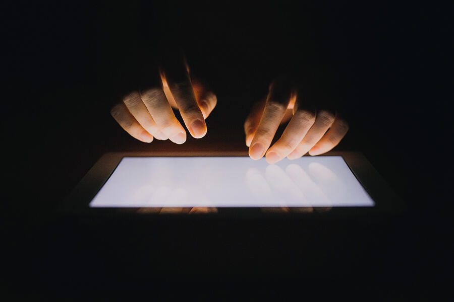 Close up of human hands typing on digital tablet against black background Photograph by D3sign