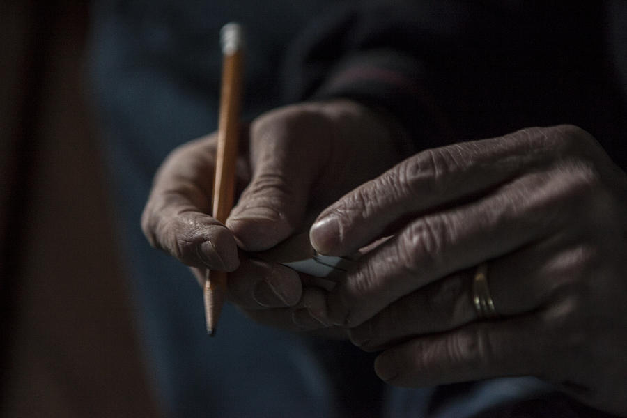 Close up of male hands holding a pencil and piece of wood Photograph by Raphye Alexius