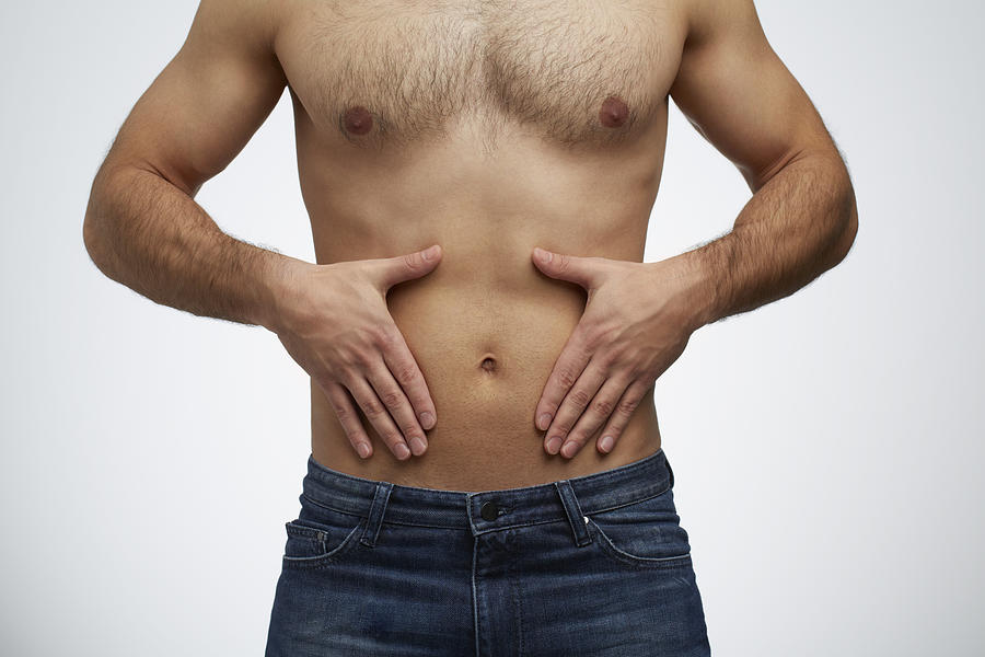Close-up of man having stomach pain (front view) Photograph by Klaus Vedfelt