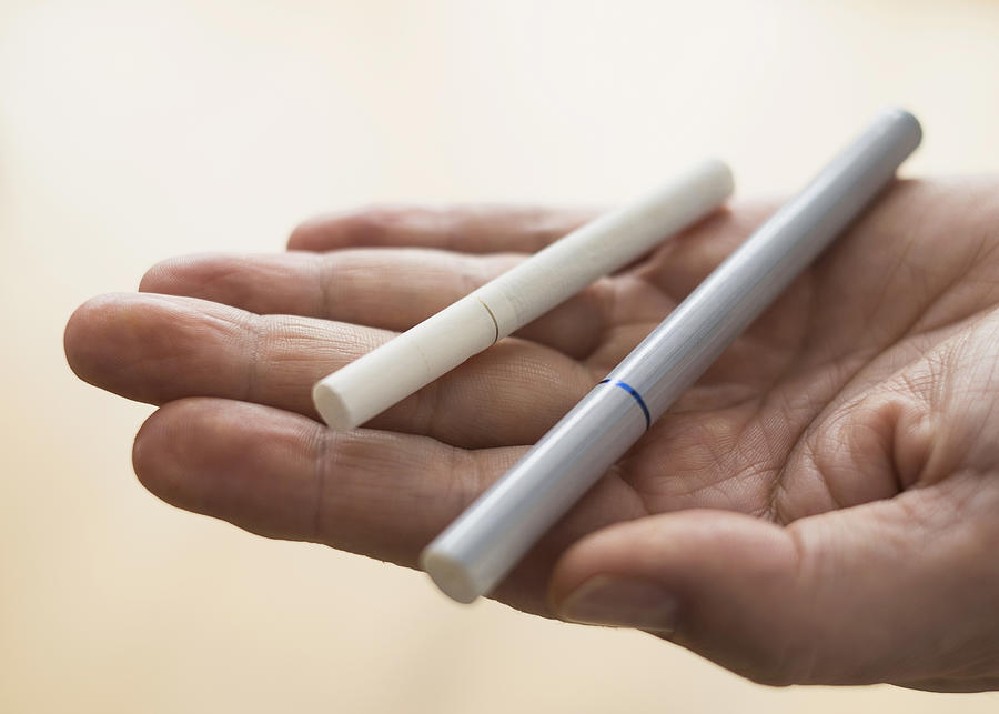 Close up of mans hand holding cigarette and e-cigarette Photograph by Tetra Images