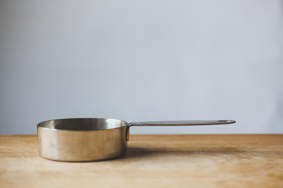 Close-up of measuring cup on wooden table against white wall Photograph by Cavan Images