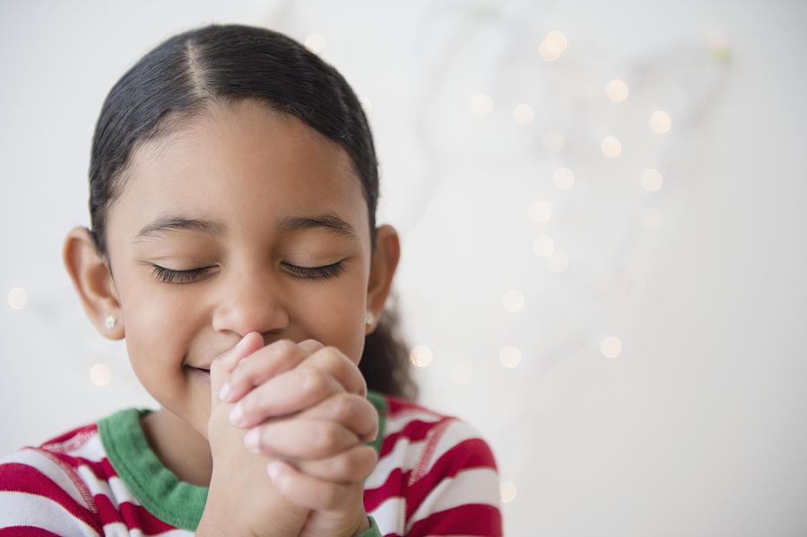 Close up of mixed race girl praying at Christmas Photograph by JGI/Jamie Grill