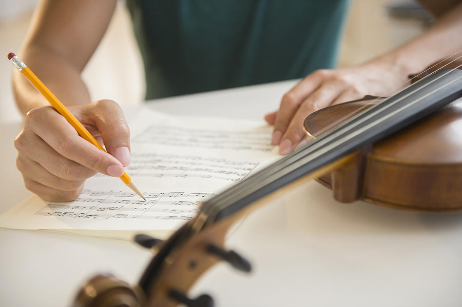Close up of mixed race man writing sheet music for violin Photograph by JGI/Jamie Grill