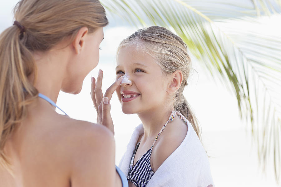 Close-up of mother applying suntan lotion on daughters nose Photograph by OJO Images