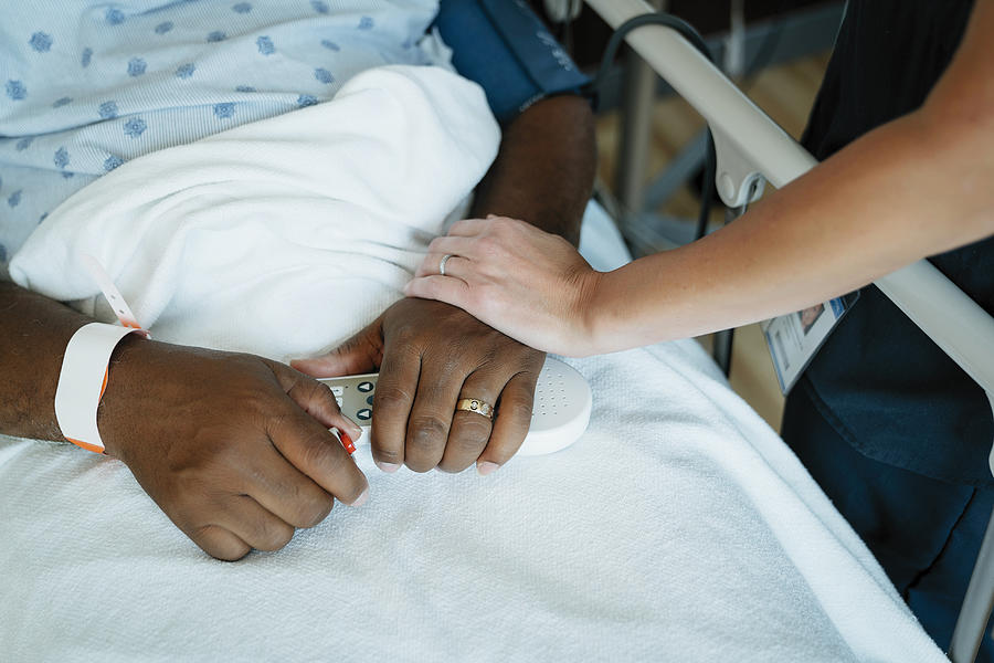 Close-up of nurse touching senior patients hand in hospital ward Photograph by Cavan Images