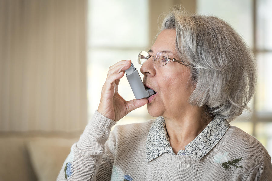 Close up of older Hispanic woman using asthma inhaler Photograph by Terry Vine