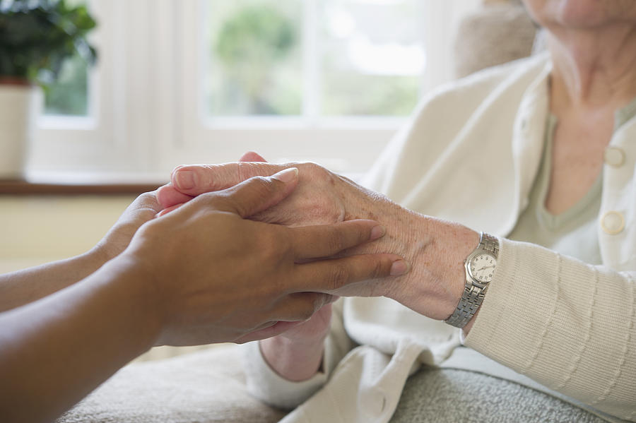 Close up of older woman and caretaker holding hands Photograph by Jacobs Stock Photography Ltd