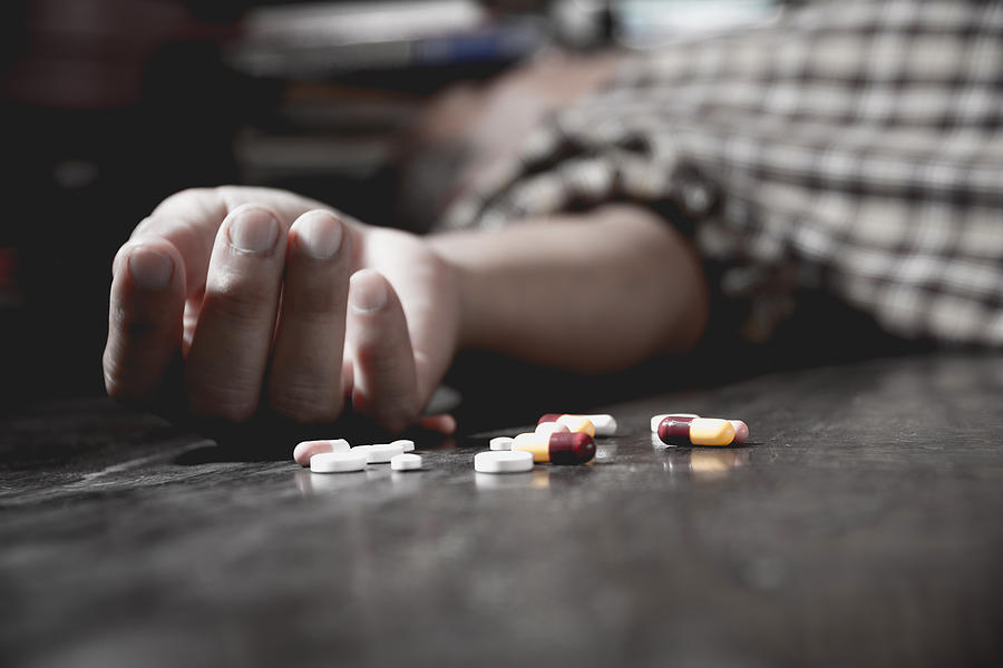 Close up of overdose pills and addict. Photograph by Kirisa99