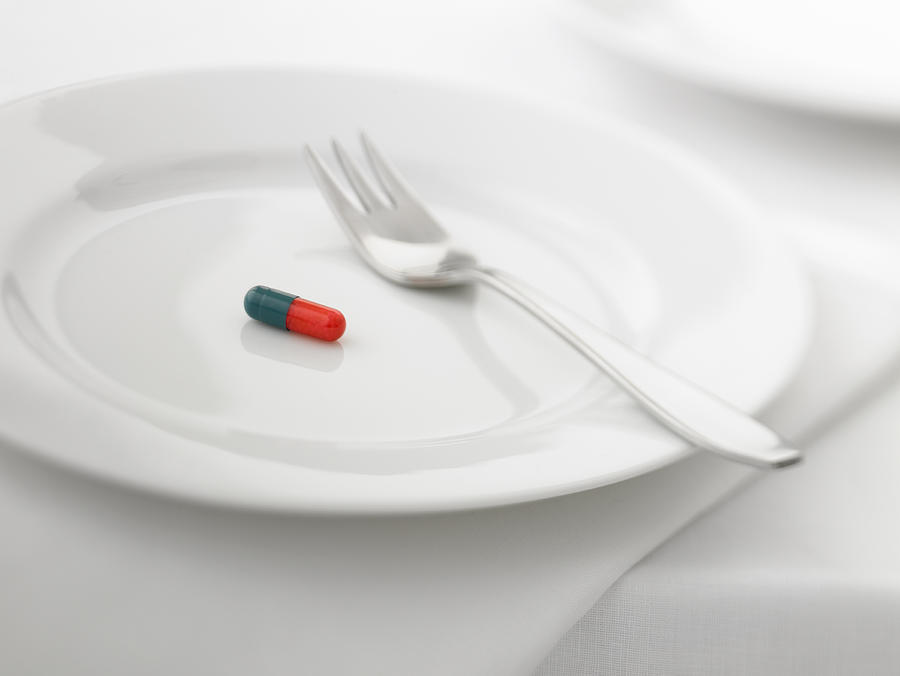 Close up of pill capsule on plate Photograph by Adam Gault