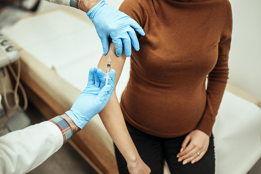 Close up of pregnant woman getting vaccinated Photograph by Bogdankosanovic