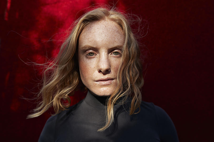 Close-up of serious woman standing against red wall Photograph by Klaus Vedfelt