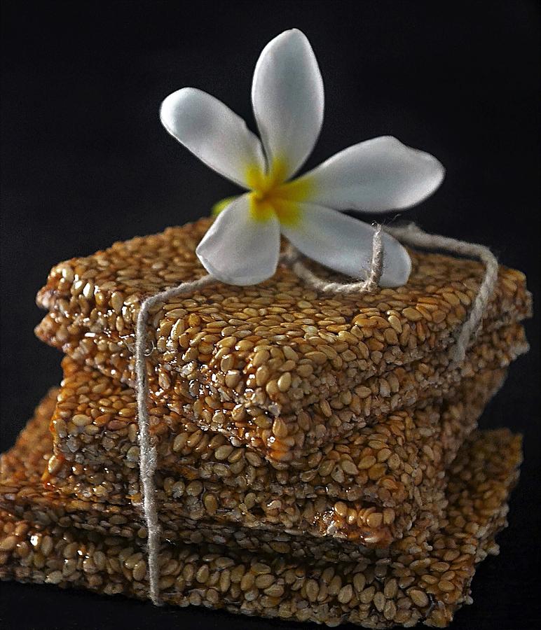 Close-up of sesame brittle/chikki and frangipani flower Photograph by Veena Nair