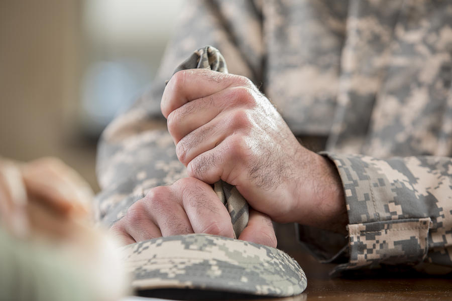 Close up of soldiers hands holding hat in counseling session Photograph by SDI Productions