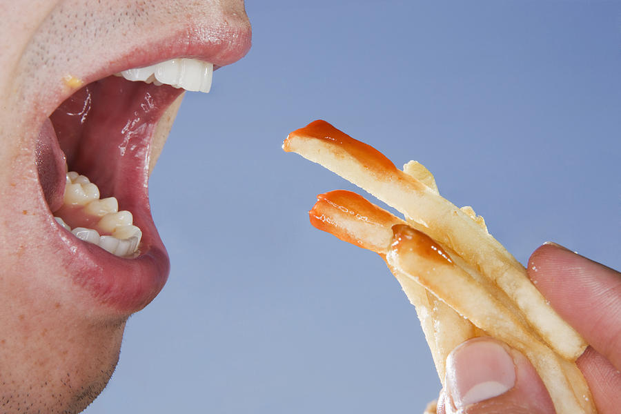 Close-up of someone eating french fries Photograph by Sian Kennedy
