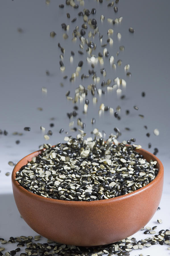 Close-up of Split Black grams falling down into a bowl Photograph by PhotosIndia.com