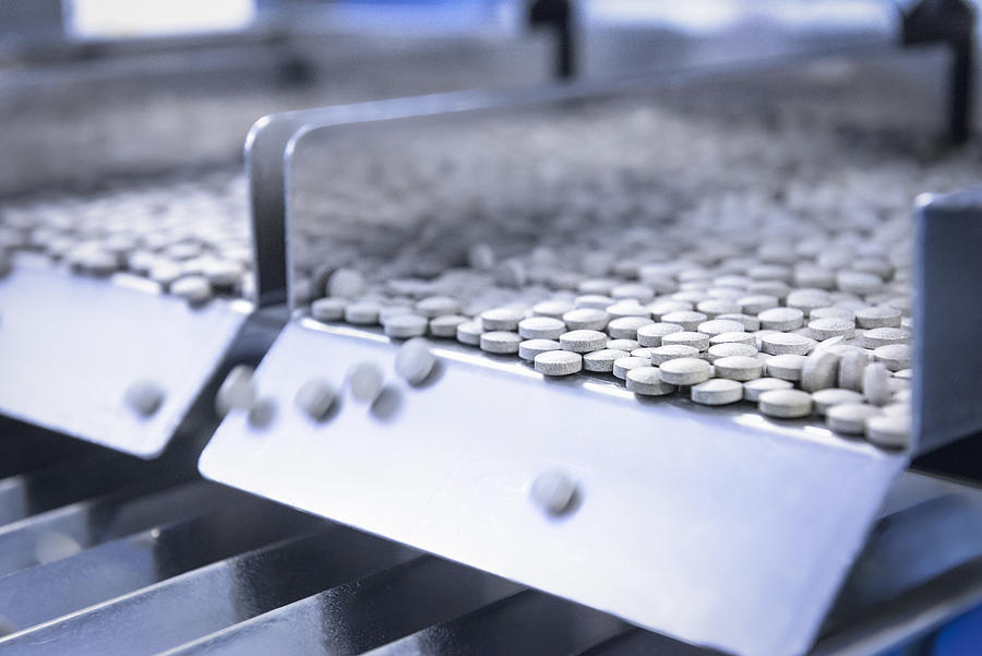 Close up of tablets in packing machine in pharmaceutical factory Photograph by Monty Rakusen