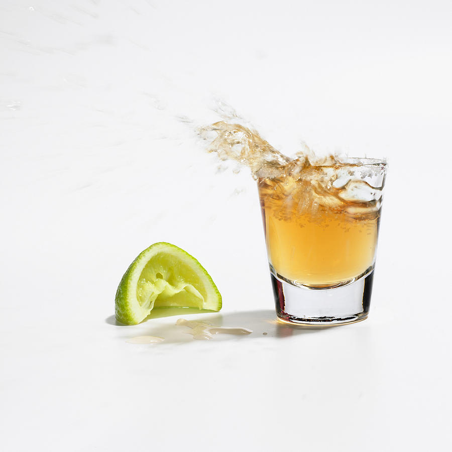 Close up of tequila splashing out of glass Photograph by Kevin Twomey