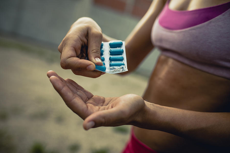 Close up of unrecognizable athletic woman taking supplements. Photograph by Skynesher